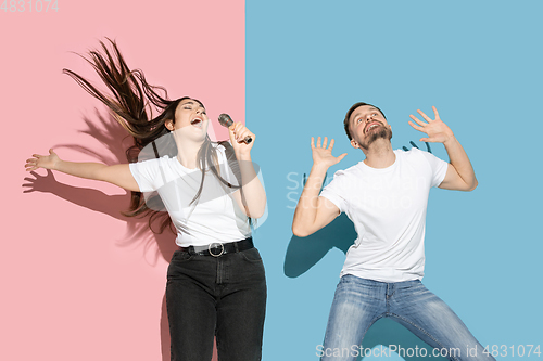 Image of Young emotional man and woman on pink and blue background