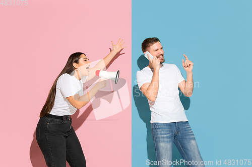 Image of Young emotional man and woman on pink and blue background