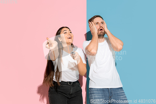 Image of Young emotional man and woman on pink and blue background