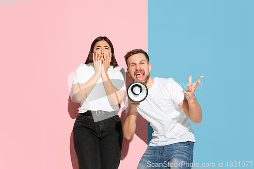 Image of Young emotional man and woman on pink and blue background