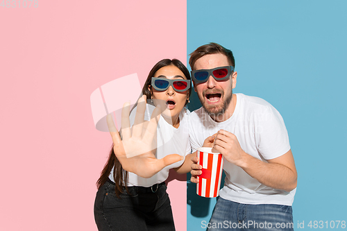 Image of Young emotional man and woman on pink and blue background