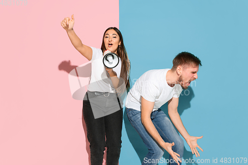 Image of Young emotional man and woman on pink and blue background