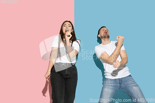 Image of Young emotional man and woman on pink and blue background