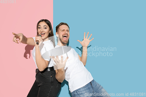 Image of Young emotional man and woman on pink and blue background