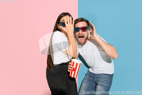 Image of Young emotional man and woman on pink and blue background