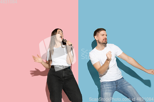 Image of Young emotional man and woman on pink and blue background