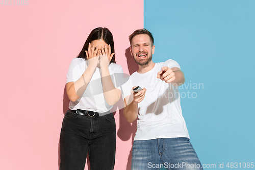 Image of Young emotional man and woman on pink and blue background