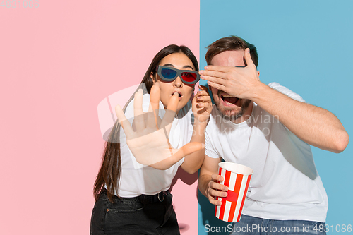 Image of Young emotional man and woman on pink and blue background