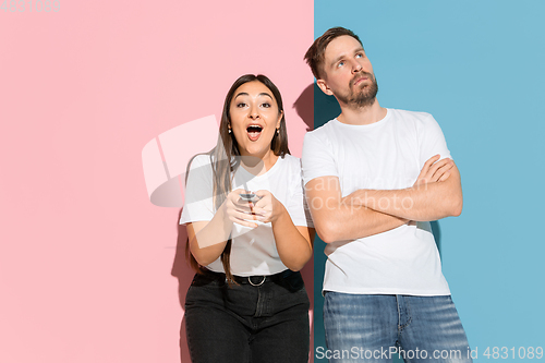 Image of Young emotional man and woman on pink and blue background