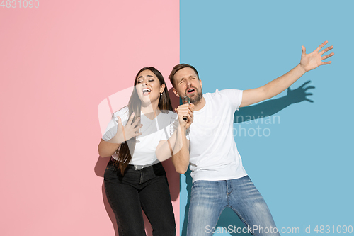 Image of Young emotional man and woman on pink and blue background