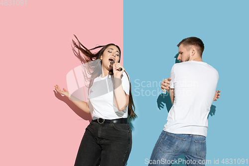 Image of Young emotional man and woman on pink and blue background