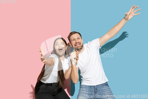 Image of Young emotional man and woman on pink and blue background