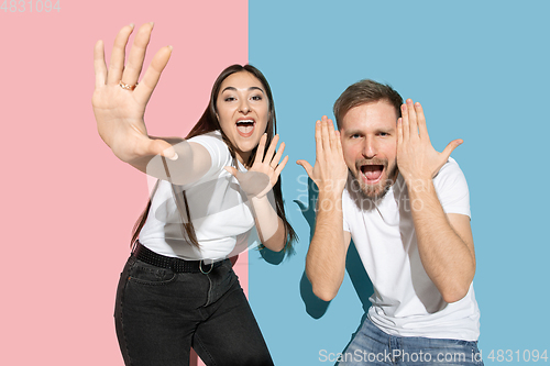 Image of Young emotional man and woman on pink and blue background