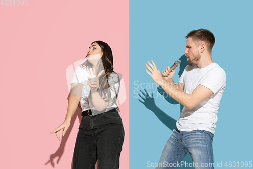 Image of Young emotional man and woman on pink and blue background