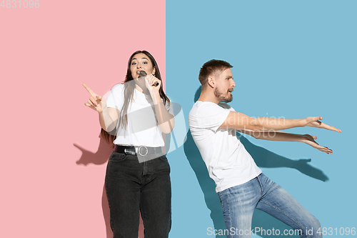 Image of Young emotional man and woman on pink and blue background