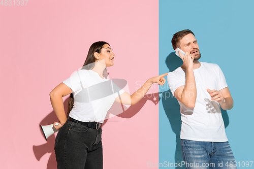 Image of Young emotional man and woman on pink and blue background