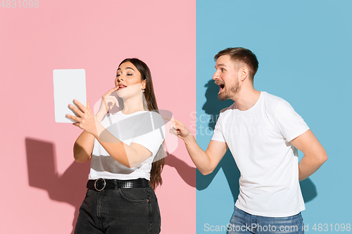Image of Young emotional man and woman on pink and blue background