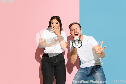 Image of Young emotional man and woman on pink and blue background