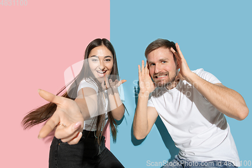 Image of Young emotional man and woman on pink and blue background