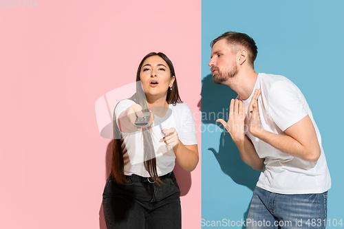 Image of Young emotional man and woman on pink and blue background