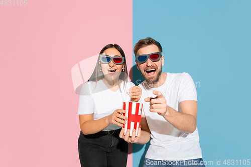 Image of Young emotional man and woman on pink and blue background