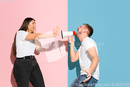 Image of Young emotional man and woman on pink and blue background