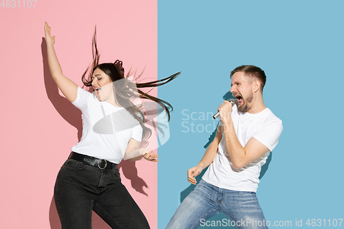 Image of Young emotional man and woman on pink and blue background