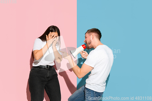 Image of Young emotional man and woman on pink and blue background