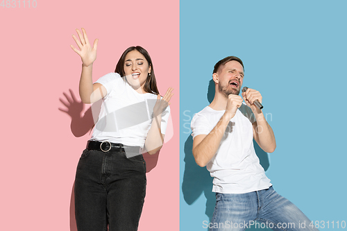 Image of Young emotional man and woman on pink and blue background