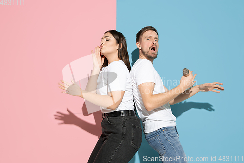 Image of Young emotional man and woman on pink and blue background