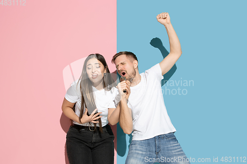 Image of Young emotional man and woman on pink and blue background