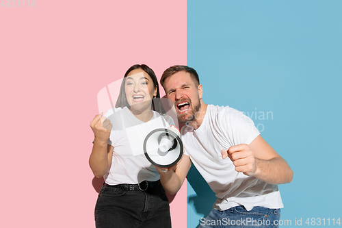 Image of Young emotional man and woman on pink and blue background