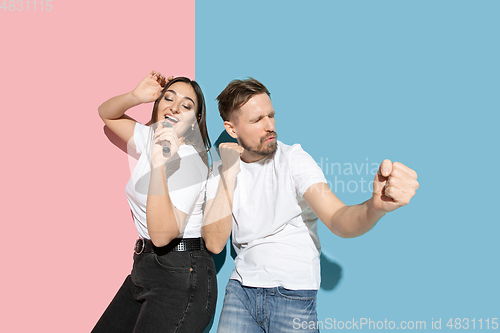 Image of Young emotional man and woman on pink and blue background