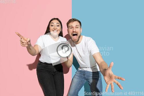 Image of Young emotional man and woman on pink and blue background