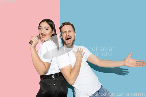 Image of Young emotional man and woman on pink and blue background