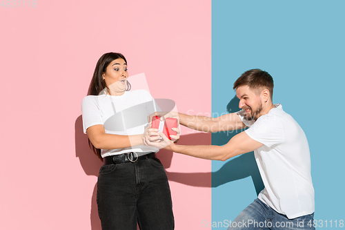 Image of Young emotional man and woman on pink and blue background