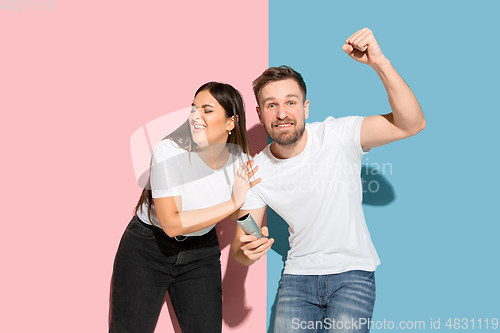 Image of Young emotional man and woman on pink and blue background