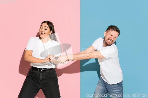 Image of Young emotional man and woman on pink and blue background