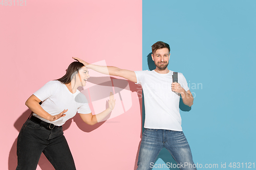 Image of Young emotional man and woman on pink and blue background