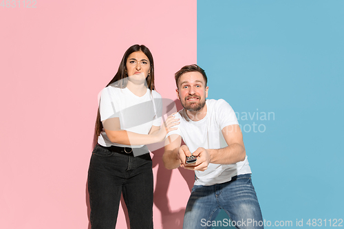 Image of Young emotional man and woman on pink and blue background