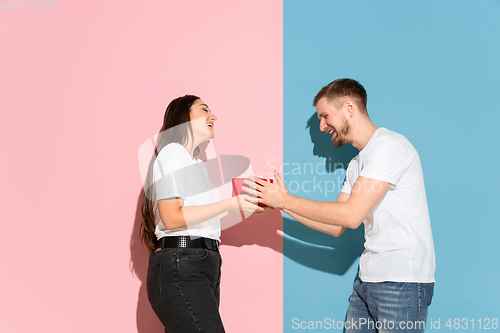 Image of Young emotional man and woman on pink and blue background