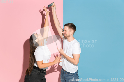Image of Young emotional man and woman on pink and blue background