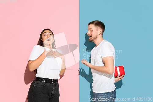 Image of Young emotional man and woman on pink and blue background