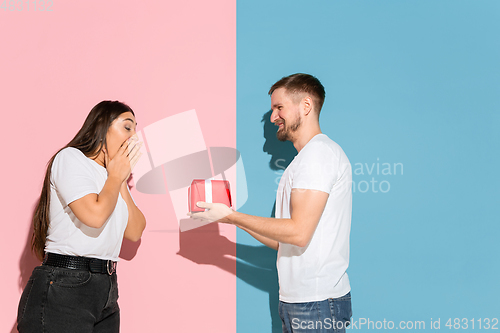 Image of Young emotional man and woman on pink and blue background