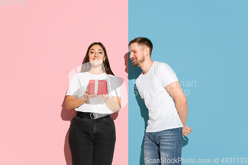 Image of Young emotional man and woman on pink and blue background