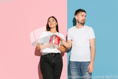 Image of Young emotional man and woman on pink and blue background