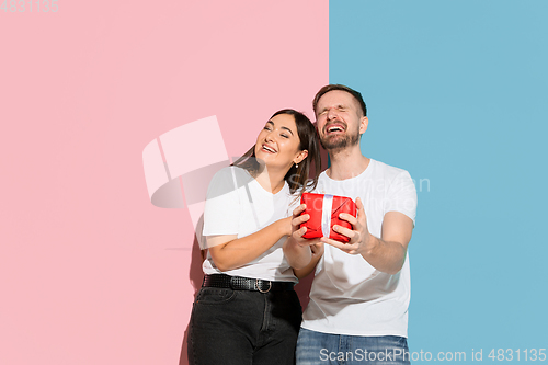 Image of Young emotional man and woman on pink and blue background