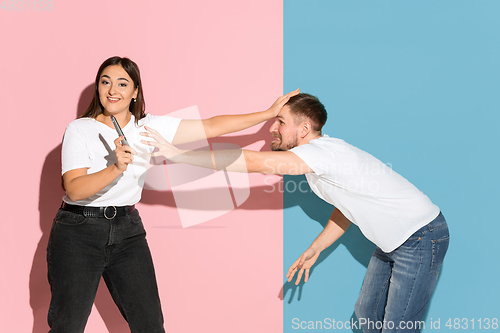 Image of Young emotional man and woman on pink and blue background