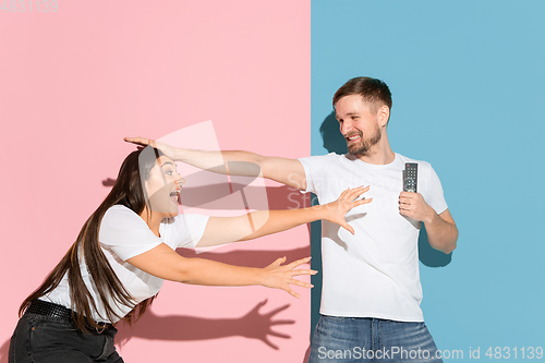 Image of Young emotional man and woman on pink and blue background