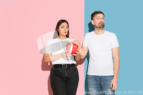Image of Young emotional man and woman on pink and blue background